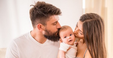 Vater und Mutter küssen ihr Baby