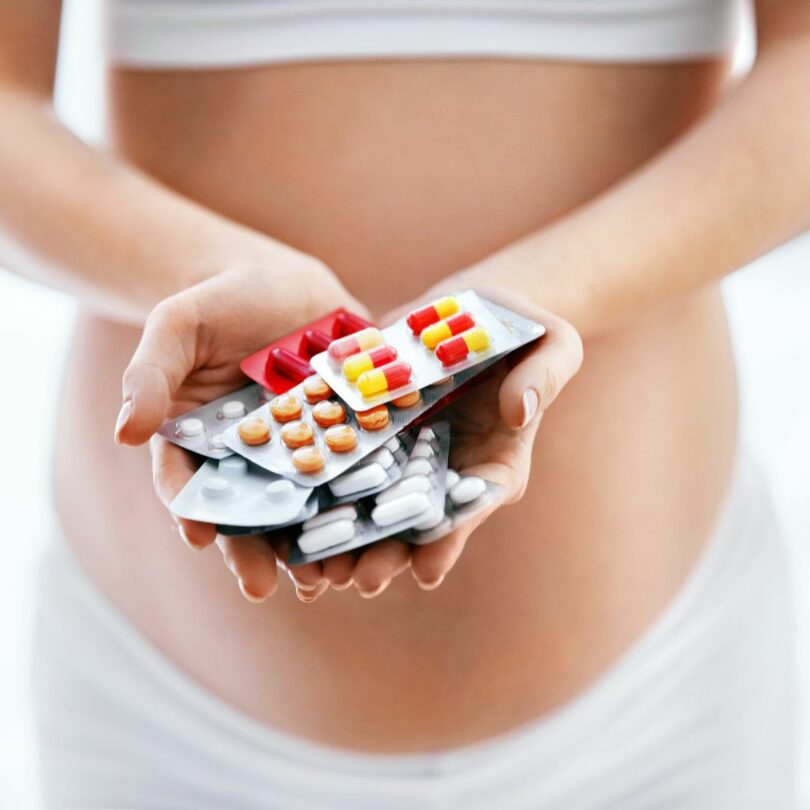 schwangere Frau hält verschiedene Medikamente und Arzneimittel in der Hand